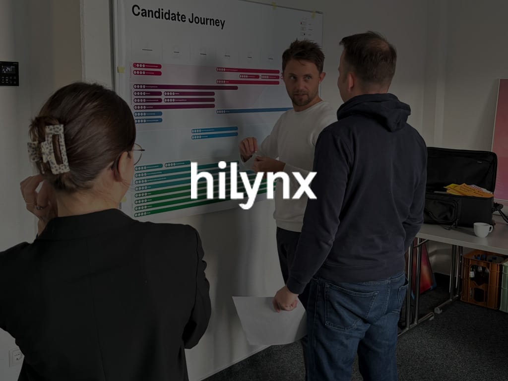 Drei Personen diskutieren an einer Wandtafel mit dem Titel 'Candidate Journey' bei hilynx.