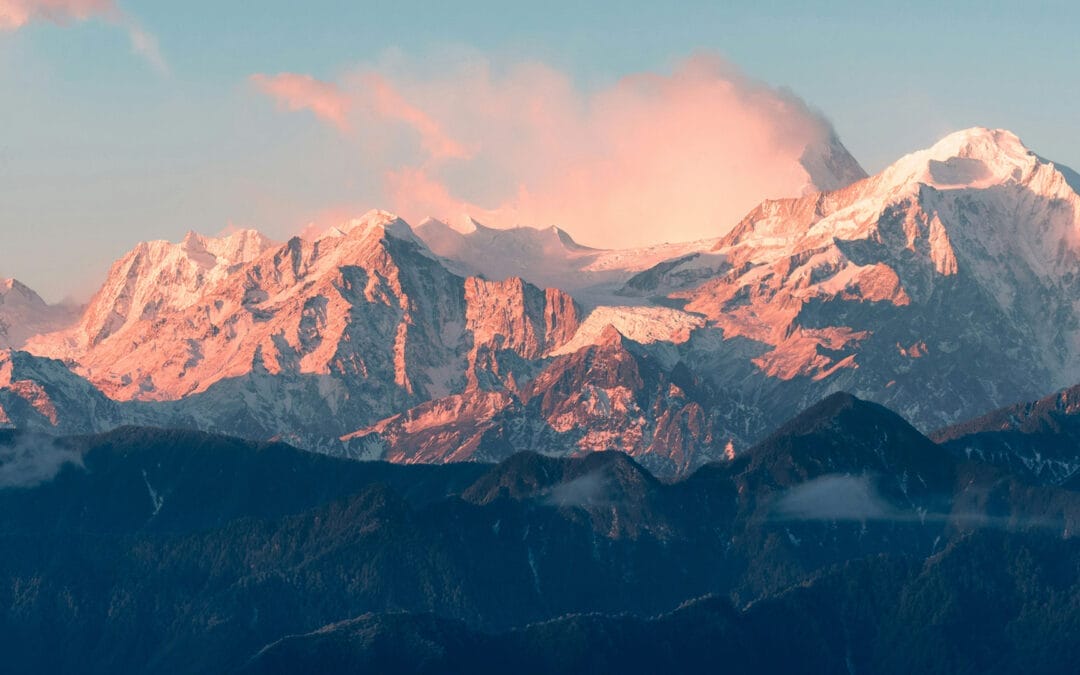Berglandschaft mit schneebedeckten Gipfeln und sanften Wolken im Himmel.